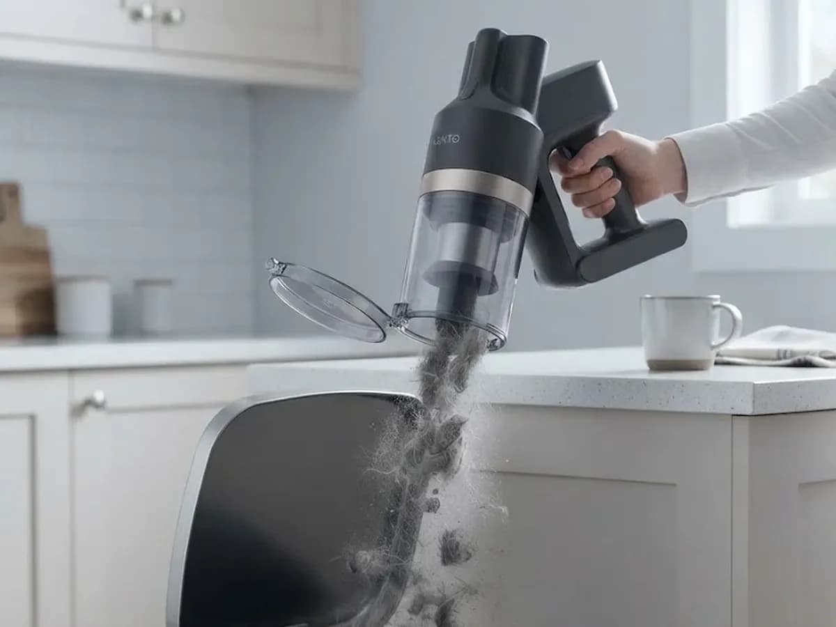 The Vekto Stick held over a kitchen bin with its bin open and dust and hair dropping out