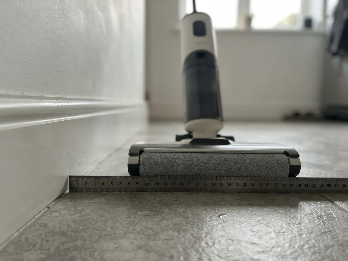 A steel ruler laid on a tiled floor against a white skirting board next to the Vekto Floor Washer F40 head, showing a 6 mm dry strip